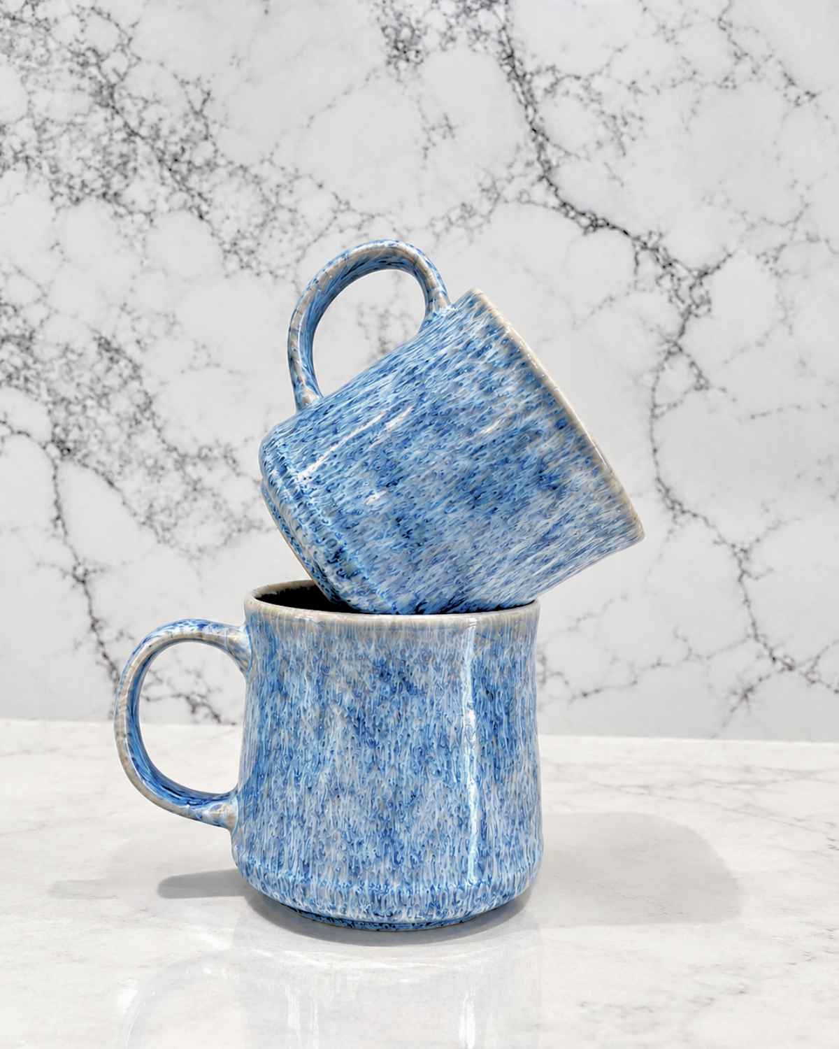Ceramic Coffee Mugs: Why No Two Reactive Glaze Mugs Are the Same, and How to Choose Yours | Upper Street Home Two speckled blue reactive glaze mugs stacked on a marble worktop